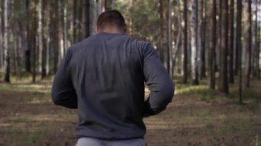 Orman yolda çalışan kas Çalıştırıcısı. Arkadan Görünüm. Orman yolda koşan atletik adam. Sonbahar orman ile iz üzerinde koşan atletik adam