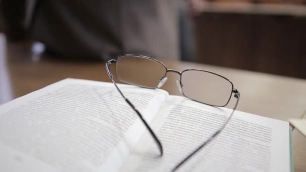 Cuaderno blanco con vasos sobre mesa de madera. Profesor de gafas en la mesa — Vídeos de Stock