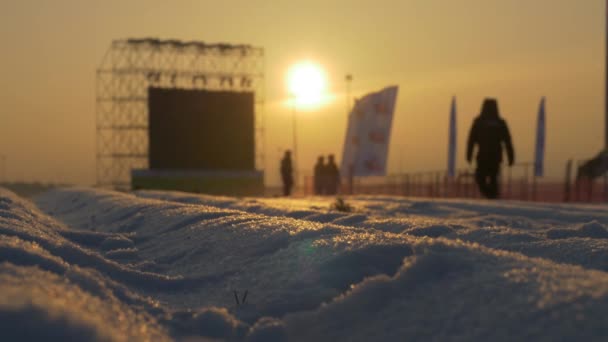 Ηλιοβασίλεμα πάνω από το λευκό χιονισμένο δρόμο, στέκεται δίπλα από το στάδιο — Αρχείο Βίντεο