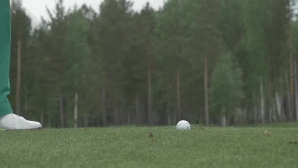 关闭的男人打高尔夫球杆在草地上。高尔夫球球在击中由驱动程序同时在练习场练习后的空气。罢工的高尔夫球在草地上 — 图库视频影像