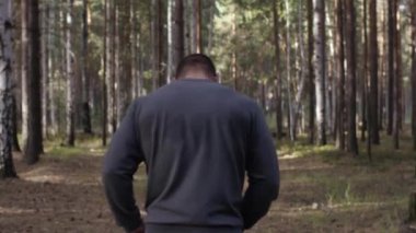 Orman yolda çalışan kas Çalıştırıcısı. Arkadan Görünüm. Orman yolda koşan atletik adam. Sonbahar orman ile iz üzerinde koşan atletik adam