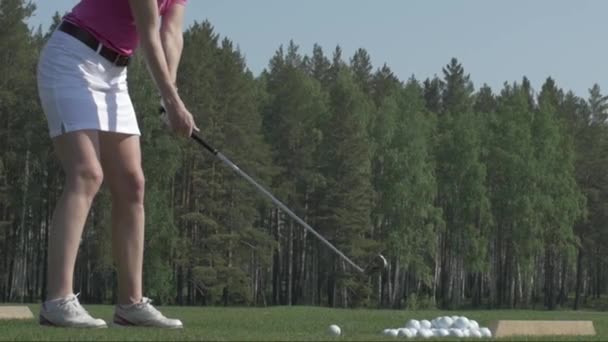 若い女性ゴルフ選手がクラブとグリーンのトレーニングします。女の子は、ボールを蹴る — ストック動画