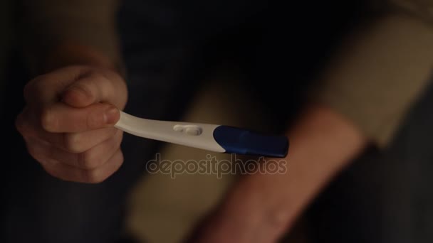 Męskiej ręki trzymającej pozytywny wynik testu ciążowego z bliska. Mężczyzna ręce, trzymając test ciążowy i umieścić go. Zdenerwowany mężczyzna mąż o ciąży wyniki badań. — Wideo stockowe