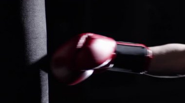 Kum torbası - adam ile A dövme boks üzerinde karanlık bir arka plan ile bazı başladı pratik savaşçısı. Tekme, koyu arka plan üzerinde kum torbası. Siyah kum torbası spor salonunda ağırlığında