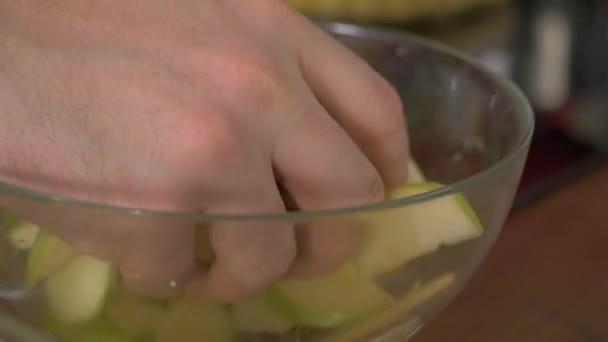 Mezclar a mano las rodajas de manzana en un bol de cerca. Alimentación saludable, cocina, comida vegetariana, dieta y concepto de personas — Vídeo de stock