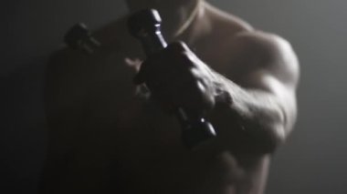 Savaşçı trenlerle dilsiz çanları. Sporcu trenler ve dumbbells ile egzersizleri yapın. Seksi kaslı adam
