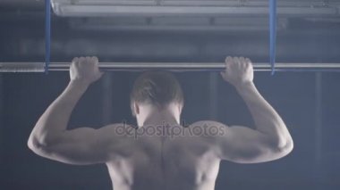 Arkadan Görünüm kaslı adamın çıplak gövde yatay çubuk çekme ups egzersiz yapıyor. Fitness, spor olarak jimnastik çalışma. Adam çıplak gövde ile çekiyor çubuğunda arkadan görünüm