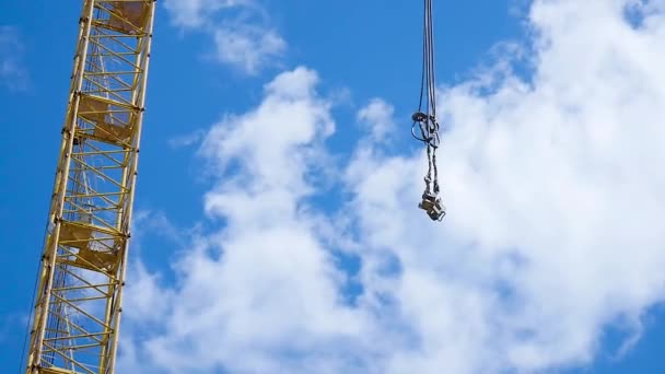 Primer plano de una pluma de grúa amarilla y verde con el bloque principal y la pluma contra un cielo azul claro. Torre de construcción de grúas contra el cielo . — Vídeos de Stock