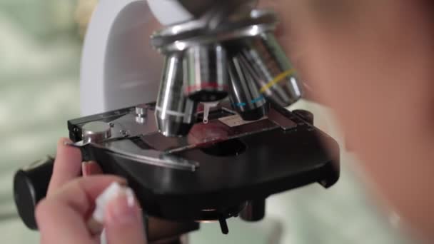 Κοντινό πλάνο, εξέταση του δείγματος στο μικροσκόπιο στο εργαστήριο. Κοντινό πλάνο του μικροσκοπίου στο εργαστήριο αίματος. Μικροσκόπιο στο εργαστήριο και τα χέρια του επιστήμονα, κοντινό πλάνο — Αρχείο Βίντεο