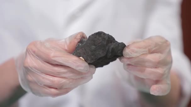 Чоловічі руки в рукавичках тримають вугілля. Вчений із зразком вугілля. Чорне вугілля в руці шахтарів — стокове відео