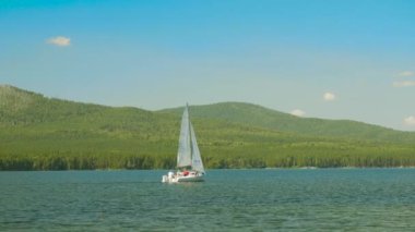 Yelkenli su. Yelkenliler güzel göl kenarında. Gölde yüzen beyaz yelkenli