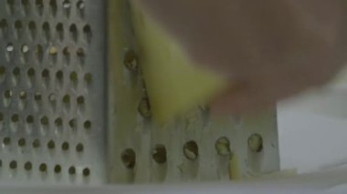 Kadın peynir rende üzerinde sürtünme. Peynir parçalarını aşağı asmak. Peynir rende üzerinde el losyonları