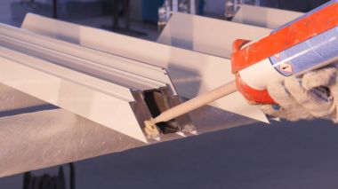 Pencere kapalı onarmak için silikon tüp kullanarak çalışan eller. Alüminyum pencere ayrıntılar. İnşaat işçisi pencere işyerinde yükleme. İhtiyar bir silikon tüp için kullanarak Backview