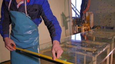 İşçi temiz ve kuru cam imalatı. Orta yetişkin çalışan temizlik sabun sud cam pencere üzerinde çekçek ile gülümseyen. Çalışan yıkama pencere stand büyük bardak. Su alt temiz cam kullanarak 