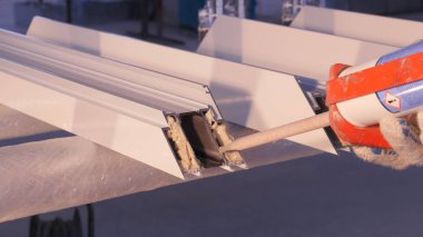 Pencere kapalı onarmak için silikon tüp kullanarak çalışan eller. Alüminyum pencere ayrıntılar. İnşaat işçisi pencere işyerinde yükleme. İhtiyar bir silikon tüp için kullanarak Backview