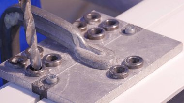 Alüminyum ve metal elektrikli matkap kullanarak delinmiştir delik. Alüminyum veya metal metal atölyesinde closeup elektrikli matkapla Delme. Yassı çelik plaka Delme tezgah matkap ile çalışan.
