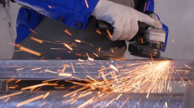 Disk öğütücü atölye ile metal testere ustası. Metal kıvılcım uçan taşlama. Çelik fabrika düşük hızlı çekim yapısında taşlama elektrikli tekerlekli. metal ile turuncu uçan taşlama
