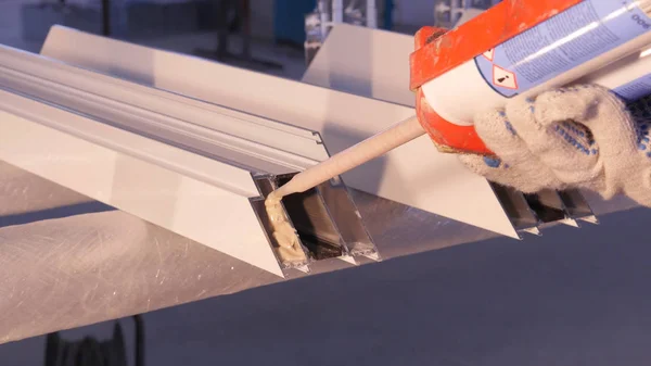 Les mains du travailleur à l'aide d'un tube en silicone pour la réparation de la fenêtre intérieure. Détails de fenêtre en aluminium. Ouvrier de la construction installant fenêtre sur le lieu de travail. Backview de vieil homme en utilisant un tube en silicone pour — Photo