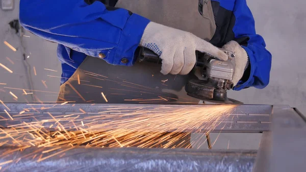 Artesanato serrar metal com moedor de disco na oficina. Moagem de metal com faíscas voando. Roda elétrica moagem em estrutura de aço na fábrica obturador de baixa velocidade. moagem de metal com laranja voando — Fotografia de Stock