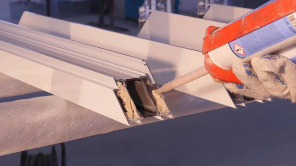 Les mains du travailleur à l'aide d'un tube en silicone pour la réparation de la fenêtre intérieure. Détails de fenêtre en aluminium. Ouvrier de la construction installant fenêtre sur le lieu de travail. Backview de vieil homme en utilisant un tube en silicone pour — Photo