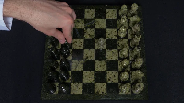 Checkmate. Start Of A Chess Game,the Figures Are Lined Up And A Person Makes The First Move. Hand moving a knight chess piece on chessboard. Mans hands play chess, checkmate in chess — Stock Photo, Image