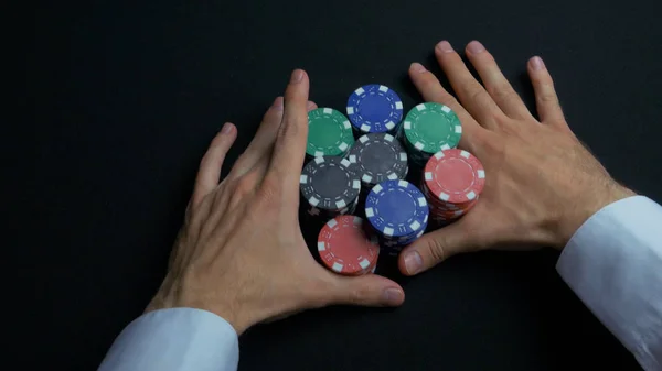 Una pila de fichas de póquer y dos manos en la mesa. Primer plano de fichas de póquer en pilas en la superficie de la mesa de fieltro verde. fichas de póquer y las manos por encima de ella en la mesa verde. Distribuidor — Foto de Stock