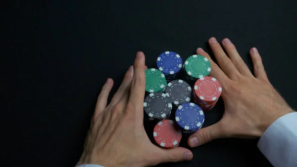 Pilha de fichas de poker e duas mãos na mesa. Closeup de fichas de poker em pilhas na superfície da mesa de cartão de feltro verde. Fichas de poker e mãos acima dele na mesa verde. Comerciante — Fotografia de Stock