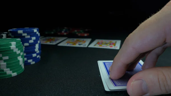 Persona che mostra il suo mazzo alla partita di poker. Giocatore di carte controlla la sua mano, due assi in, chip in background sul tavolo da gioco verde, concentrarsi sulla carta. Mano di due assi nel poker — Foto Stock