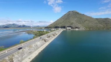 Köprü mavi deniz, dağlar ve gökyüzü arka plan üzerinde siyah araba. Görüntüleri. Araba hava görünümünü Nehri yakınında bir yolda gidiyor. Görüntüleri. Küçük orman Gölü ve otoyol yakınında geçen bir çizgi, havadan görünümü