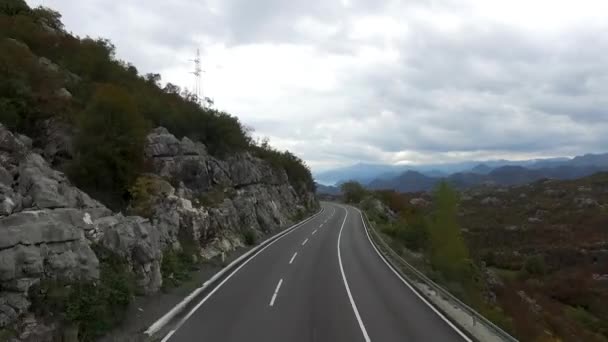 Strada attraverso le colline erbose. Voce principale: Mountain road. Giornata estiva nuvolosa. Viaggia in auto. Auto attraversare strada di montagna tortuoso al crepuscolo — Video Stock