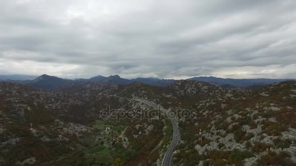 Flygfoto på landskap med bil på bergsväg. Footage. Mossiga grönt gräs och vacker utsikt över dalen med sjöar och dramatisk himmel och moln. Antenn skott mellan höga berg i en liten — Stockvideo