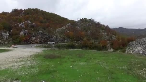 Pejzaż panoramiczny strzał z samochodem między górami i piękne niebieskie niebo. Materiał filmowy. Kręta droga między Gór Skalistych — Wideo stockowe