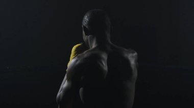 Kaslı adam siyah arka plan üzerine boks dikiz. Gölge boks pratik Afro Amerikan genç erkek boxer. Sarı boks eldivenleri boksör