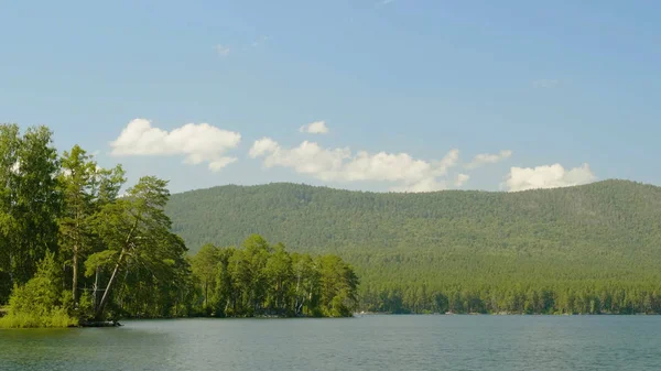Eau bleue dans un lac forestier avec des pins. Beau lac et forêt verte — Photo