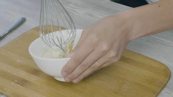 Крупный план человека руки взбивая яйца в миску для приготовления пищи — стоковое фото