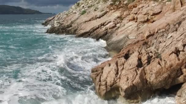 Vågorna bryta på en stenig strand, bildar en spray. Footage. Stänkande vågor på klipporna över havet — Stockvideo