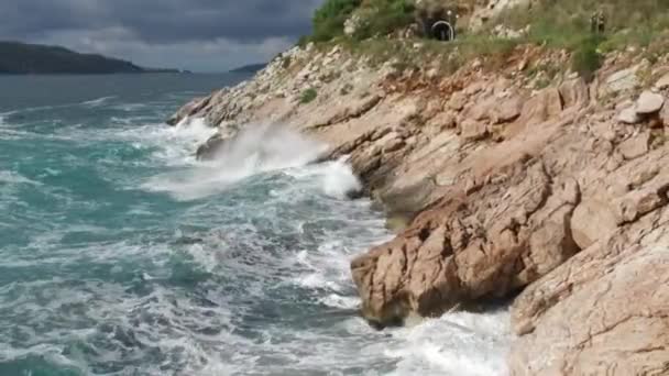 Vågorna bryta på en stenig strand, bildar en spray. Footage. Stänkande vågor på klipporna över havet — Stockvideo