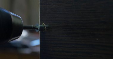 Bir elektrikli el matkabı bir Pano bir vida sürücü kullanan adam. Ortamda bulunan toz tanecikleri Parlatıcı havadaki toz. Vida sıkma