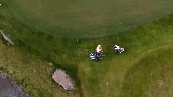 Aerial view Golf course. Golfers walking down the fairway on a course with golf bag and trolley