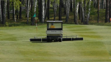 İskoç bir golf sahasının kenarında çim biçme makinesi iş. Makine için çim üzerinde Golf