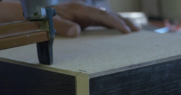 Usando a pistola de grampo para fixar o lado de trás do armário na fábrica de móveis, close-up — Fotografia de Stock