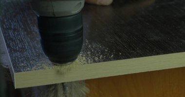Marangoz ahşap Atölyesi masada tahta üzerinde delik yapmak elektrikli matkap kullanarak el ulağı. bir delik matkap yapar
