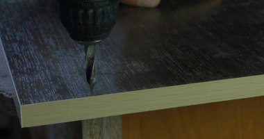 Marangoz ahşap Atölyesi masada tahta üzerinde delik yapmak elektrikli matkap kullanarak el ulağı. bir delik matkap yapar