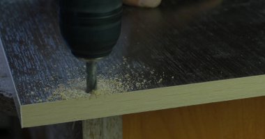 Marangoz ahşap Atölyesi masada tahta üzerinde delik yapmak elektrikli matkap kullanarak el ulağı. bir delik matkap yapar