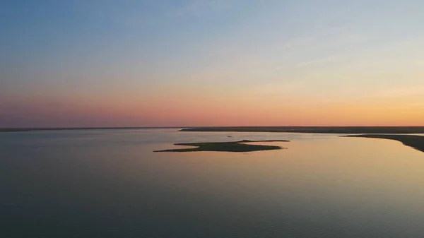 Una bandada de aves en el fondo del cielo colorido. Puesta de sol en el río. Isla de las gaviotas. Las aves vuelan al atardecer, aérea —  Fotos de Stock