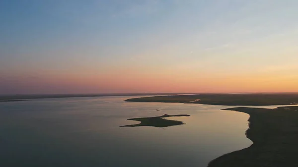 Una bandada de aves en el fondo del cielo colorido. Puesta de sol en el río. Isla de las gaviotas. Las aves vuelan al atardecer, aérea —  Fotos de Stock