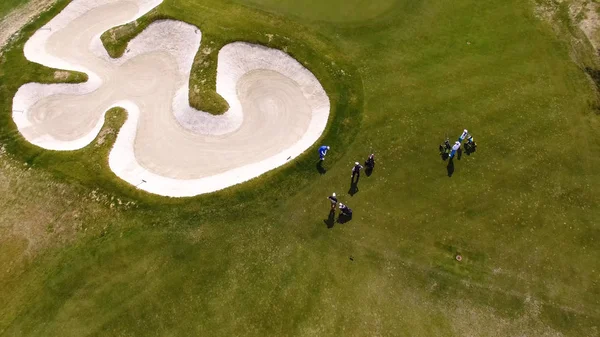 Vista aérea de golfistas jogando em colocar verde. Jogadores profissionais em um campo de golfe verde . — Fotografia de Stock