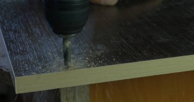 Marangoz ahşap Atölyesi masada tahta üzerinde delik yapmak elektrikli matkap kullanarak el ulağı. bir delik matkap yapar