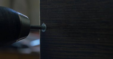 Bir elektrikli el matkabı bir Pano bir vida sürücü kullanan adam. Ortamda bulunan toz tanecikleri Parlatıcı havadaki toz. Vida sıkma