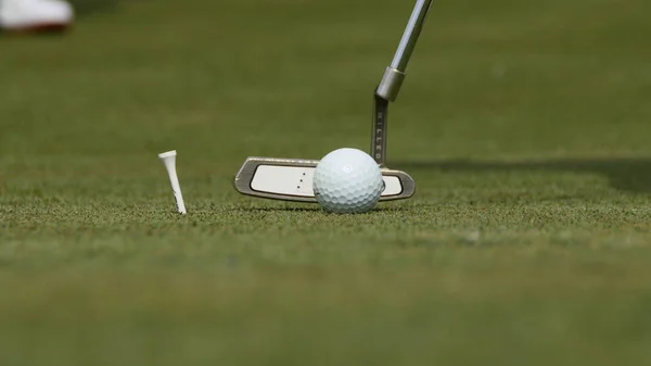 Golfprofi legt Ball ins Loch. Golfball am Lochrand mit Spieler im Hintergrund an einem sonnigen Tag — Stockfoto